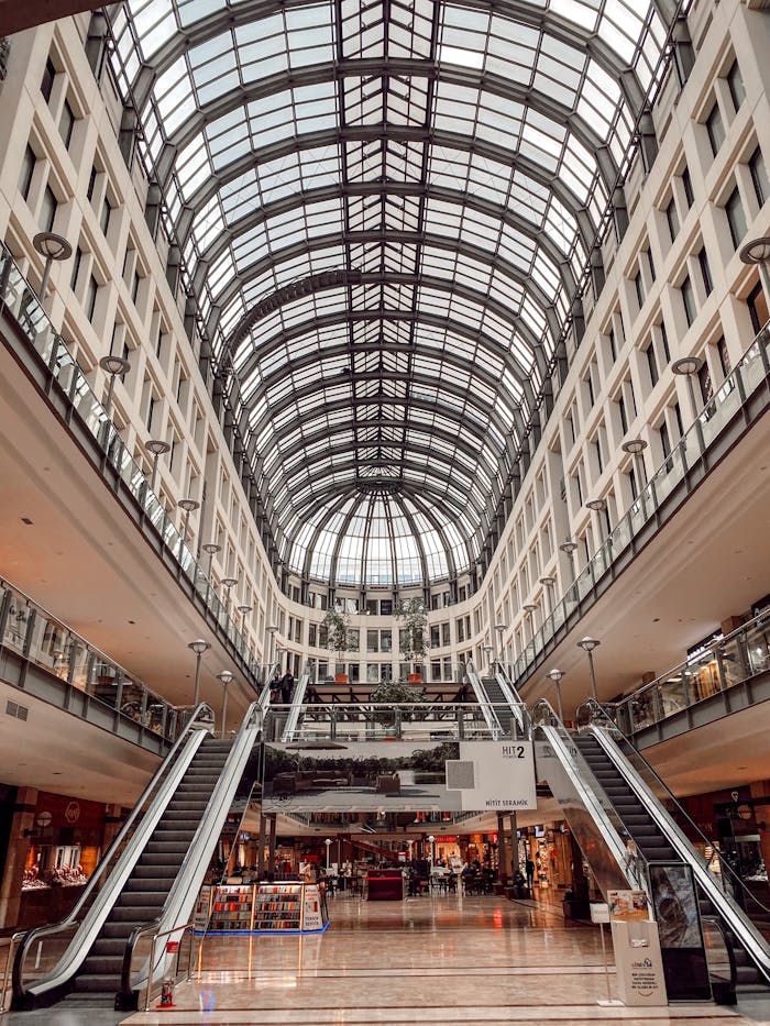 Spacious mall interior featuring grand escalators and a glass ceiling.