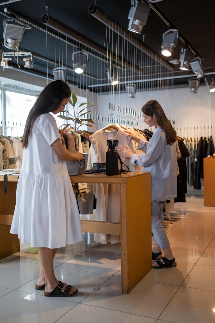 Two women browse clothing at a stylish indoor retail store.